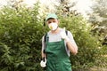 Worker with insecticide sprayer near green bush outdoors. Pest control Royalty Free Stock Photo