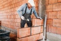 Male worker installing bricks with mortar and rubber hammer. Construction industry details