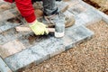 Industrial worker installing concrete paver blocks with rubber hammer and special gloves Royalty Free Stock Photo