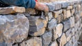 A worker installing decorative stones along the top of the wall to add a finishing touch to the structure