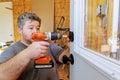 Man installs door knobs using a cordless drill in a workshop during daytime renovation Royalty Free Stock Photo