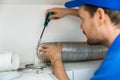 Worker installing flexible aluminum ventilation tube for kitchen cooker hood