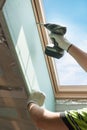 Worker installing the gypsum plaster boards near Plastic mansard or skylight window in attic room.