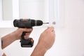 Worker installing handle on cabinet door with screw gun in kitchen, closeup Royalty Free Stock Photo