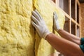 Worker installing mineral wool filling used as isolation material in walls