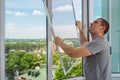 A worker installing mosquito wire screen on house plastic windows to protect from insects.