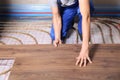 Worker installing new wooden laminate over underfloor heating system, closeup Royalty Free Stock Photo