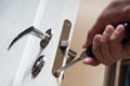 Worker installing or repairing new lock and door knob with screwdriver. Royalty Free Stock Photo