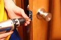 Worker installing or repairing new lock and door knob with screwdriver Royalty Free Stock Photo