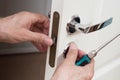 Worker installing or repairing new lock and door knob with screwdriver. Royalty Free Stock Photo