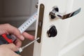 Worker installing or repairing new lock and door knob with screwdriver. Royalty Free Stock Photo