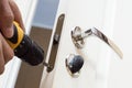 Worker installing or repairing new lock and door knob with screwdriver. Royalty Free Stock Photo