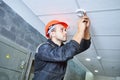 worker installing smoke detector on the ceiling. Fire alarm system installation