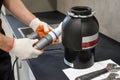 A worker is installing a waste shredder for the kitchen sink