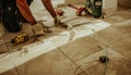 Worker installing wood flooring with tools in home renovation project, construction lines visible
