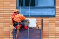 A worker installs an air conditioner on the wall of a residential building