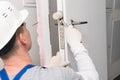 A worker installs a closing mechanism in the door with a rubber hammer