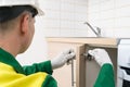 A worker installs the handle on the door of the lower cabinet of kitchen furniture using a screwdriver, side view, professional Royalty Free Stock Photo