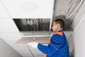 A worker installs a motion sensor in the false ceiling