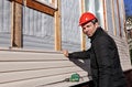 A worker installs panels beige siding on the facade Royalty Free Stock Photo