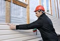 A worker installs panels beige siding on the facade Royalty Free Stock Photo