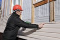 A worker installs panels beige siding on the facade Royalty Free Stock Photo