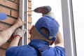 Worker installs windows craftsmen screw frame to the wall Repair in high-rise building