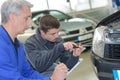 worker instructing apprentice in car wrapping workshop