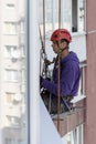 An worker insulates windows of a tall building. Hanging on ropes. Industrial alpinism.