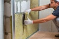 Worker insulating a room wall with mineral rock wool thermal insulation