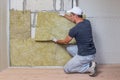 Worker insulating a room wall with mineral rock wool thermal insulation