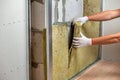 Worker insulating a room wall with mineral rock wool thermal insulation