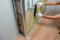 Worker insulating a room wall with mineral rock wool thermal insulation