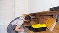 Worker in jumpsuit with toolbox looks for leakage on faucet