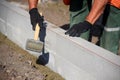 A worker knocks a hammer on the curb, sets blocks in the cement