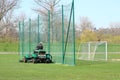 Worker on a large green lawn mower mows the grass on the football field. Landscape design and maintenance of green areas of the Royalty Free Stock Photo