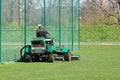 Worker on a large green lawn mower mows the grass on the football field. Landscape design and maintenance of green areas of the Royalty Free Stock Photo