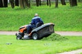 Worker at a lawnmower mowing grass on a platform in front of the Gatchina Palace.