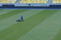 Worker lawnmower mowing lawn on football field using grass-cutter