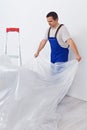 Worker laying down thin protective foil before painting Royalty Free Stock Photo