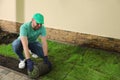 Worker laying grass sod on ground at backyard, space for text Royalty Free Stock Photo