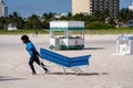 Worker laying out cushions on lounge chairs for tourists on the beach