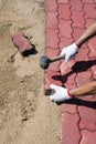 Worker laying red concrete paving blocks.