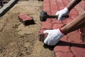 Worker laying red concrete paving blocks.