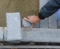 A worker lays paving slabs in even rows in the sand. Royalty Free Stock Photo