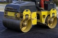 Worker leads the vibrating road roller to compact the asphalt