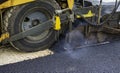 Worker leads the vibrating road roller to compact the asphalt