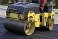 Worker leads the vibrating road roller to compact the asphalt