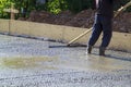 worker leveling fresh concrete slab with a special working tool