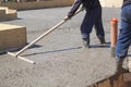 worker leveling fresh concrete slab with a special working tool